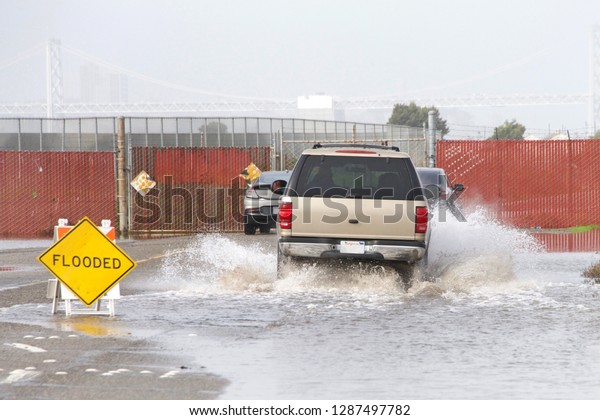 Car driving through flooded area on
road with warning sign clearly visible road
flooded.