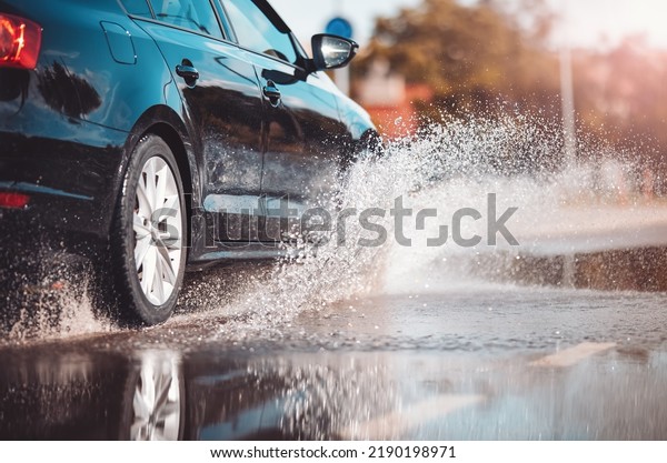 Car\
driving through the puddle and splashing by\
water.