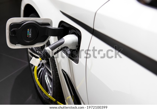 Car or Electric vehicle at charging cable\
plugged into the side of electric car. Eco-friendly sustainable\
energy concept.\
