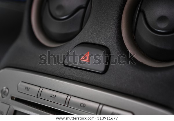 Car emergency lights button on dashboard (close up\
with dark and light)
