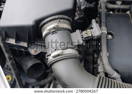 Car engine air intake sensor closeup under vehicle hood. Automotive plastic pipe and electronic connector inside modern automobile engine compartment repair background
