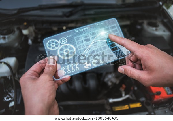 Car engine diagnostic\
concept. Car mechanic holding in hands a digital frameless computer\
with charts.