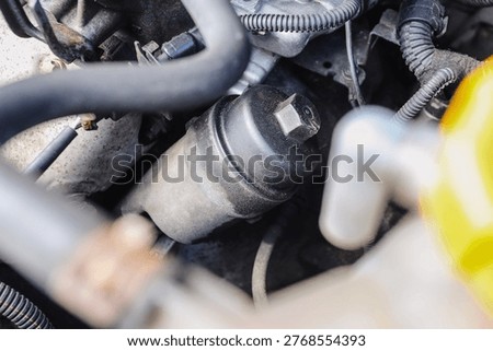 Car engine filter closeup. Black cylinder in motor bay. Mechanical service detail view. Automotive maintenance concept. Vehicle repair part inside. Workshop inspection scene.