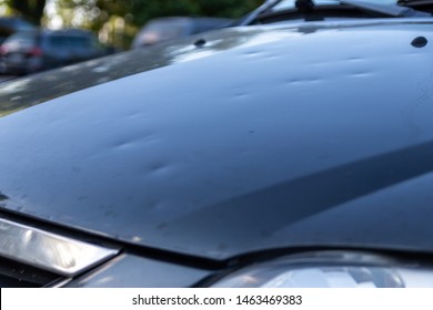 Car engine hood with many hail damage dents show the forces of nature and the importance of car insurance and a replacement value insurance against stormy weather and storm hazards or extreme weather