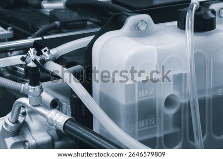 Car engine with a hose attached to a container of liquid. transport concept background