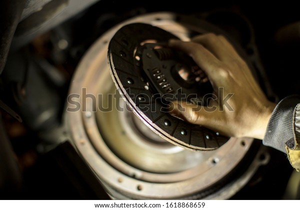 Car engine maintenance. Engine clutch\
repair. Hands with a mechanic with a clutch\
disc.