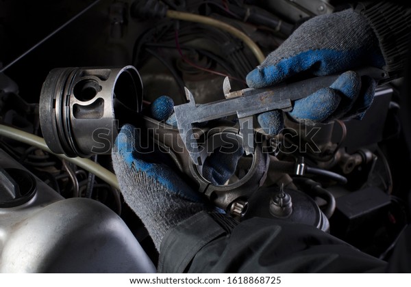 Car engine maintenance. Engine piston system\
repair. Hands with a mechanic with a caliper measure the size of\
the liner.