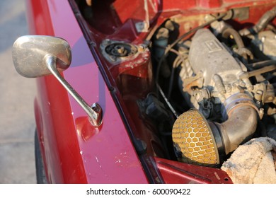 a car engine of an old car in red waiting for repairing at the roadside in the sunlight of a sunny day 