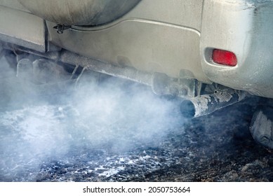 Car Engine Smoking, Smoking Exhaust Pipe, Closeup. Blue Exhaust Smoke. Car With Gasoline Or Diesel  Engine. Engine Warming Up At Idle In Winter Season.