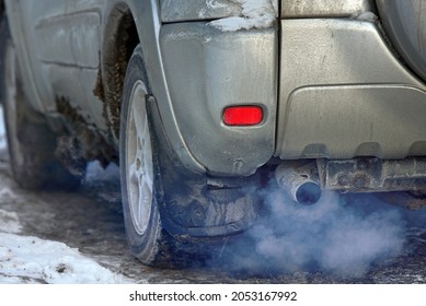 Car Engine Smoking, Smoking Exhaust Pipe, Closeup. Blue Exhaust Smoke. Car With Gasoline Or Diesel  Engine. Engine Warming Up At Idle In Winter Season.