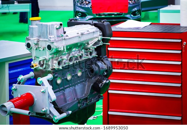 Car engine in a car workshop. The motor was\
pulled out for diagnosis. Concept - overhaul of a auto engine.\
Concept - work in a car workshop. Toolboxes. Sale of equipment for\
the automobile workshop.