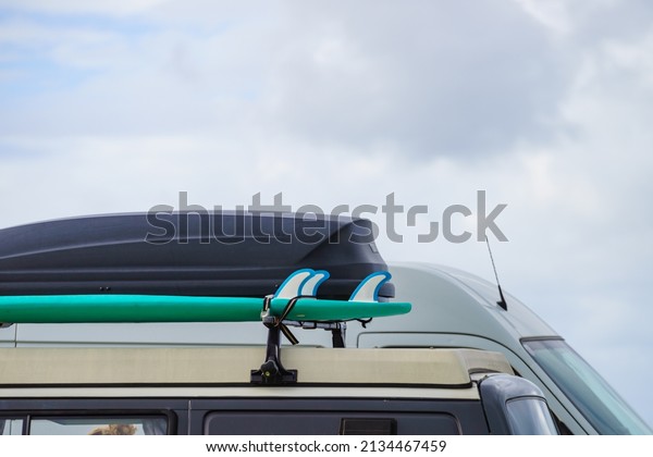 Car\
equipped with surfboard and trunk or cargo box on roof. Activity,\
holidays trip. Accessories for\
transportation.