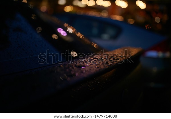 The car in the evening city is wet from the rain.\
Raindrops on a car.