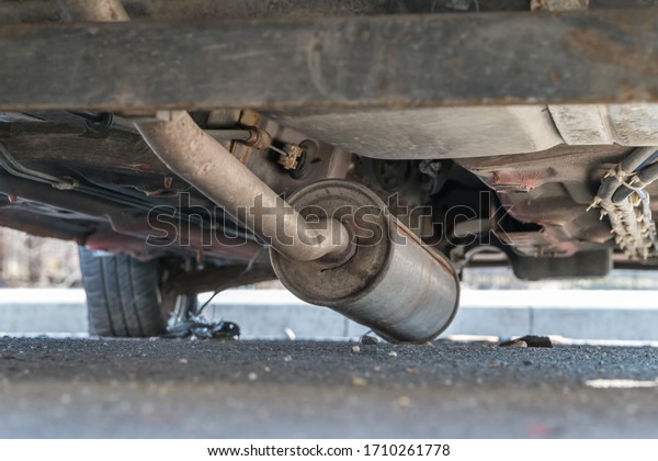Car exhaust, muffler fallen down on the ground -\
view of rusty chassis of a\
car