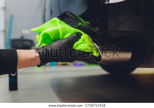 Car exhaust pipe with soap. Car wash background.\
close-up of a green rag
