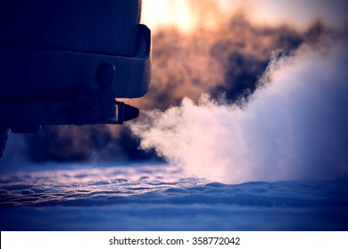 Car exhaust pipe, which comes out strongly of smoke in Finland. Focal point is the center of the photo. Background out of focus.  Image includes a effect.
