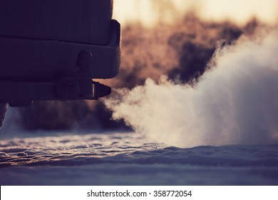 Car exhaust pipe, which comes out strongly of smoke in Finland. Focal point is the center of the photo. Background out of focus. Image includes a vintage effect.