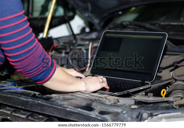 A car expert uses a laptop for\
automatic diagnostics. Computer diagnostics of a car engine. Expert\
girl, female hand on a laptop keyboard.\
Close-up.