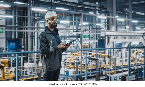 Car Factory Engineer in Work Uniform Using Tablet Computer. Automotive Industry 4.0 Manufacturing Facility Working on Vehicle Production with Robotic Arms Technology. Automated Assembly Plant. - Shutterstock ID 2072431796
