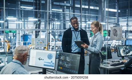 Car Factory Office: Female Engineer Talks With Male Scientist, Use Tablet Computer To Design Production Conveyor For Advanced Power Engines. Automated Robot Arm Assembly Line Manufacturing Vehicles