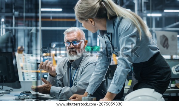 Car Factory Office:\
Manager Talks to Engineer Working on Computer. CAD Software, 3D\
Turbine Engine, Electric Car. Automated Robot Arm Assembly Line\
Manufacturing Vehicles.