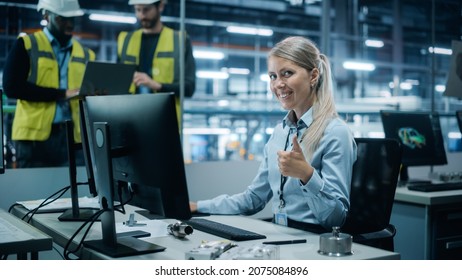 Car Factory Office: Portrait Of Female Engineer Working On Desktop Computer, Smiling And Showing Thumbs Up Gesture. Team Of Technicians In Automated Robot Arm Assembly Line Manufacturing Electronics