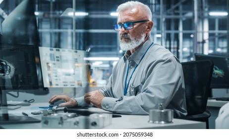 Car Factory Office: Portrait Of Senior Male Chief Engineer Working On Desktop Computer In Automated Robot Arm Assembly Line Manufacturing High-Tech Electric Vehicles. Electronics Production Conveyor