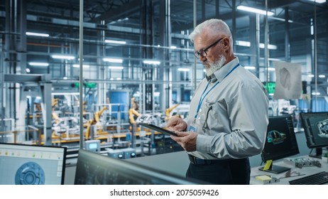 Car Factory Office: Portrait Of Senior White Male Chief Engineer Using Tablet Computer In Automated Robot Arm Assembly Line Manufacturing High-Tech Electric Vehicles. Side View Shot