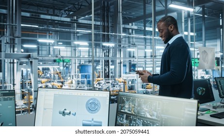 Car Factory Office: Portrait Of Successful Black Male Chief Engineer Using Tablet Computer In Automated Robot Arm Assembly Line Manufacturing High-Tech Electric Vehicles. Side View Shot