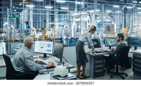 Car Factory Office: Project Manager Talks To Engineer Working On Computer. CAD Software, 3D Turbine Engine, Electric Car. Automated Robot Arm Assembly Line Manufacturing Vehicles. Wide Shot