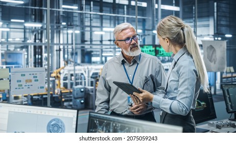 Car Factory Office: Scientist Talks with Senior Engineer, Use Tablet Computer to Design Production Conveyor for Advanced Power Engines. Automated Robot Arm Assembly Line Manufacturing Vehicles - Shutterstock ID 2075059243