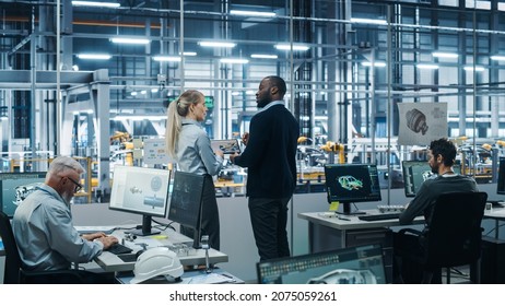 Car Factory Office: Team Of Automotive Engineers Working, Talk, Use Tablet Computers To Design Advanced 3D Models For High-Tech Engines. Automated Robot Arm Assembly Line Manufacturing Vehicles