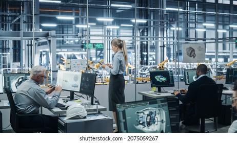 Car Factory Office: Team of Automotive Engineers Working, Using Computers to Design Advanced 3D Models for High-Tech Engines. Automated Robot Arm Industrial Assembly Line Manufacturing Vehicles
