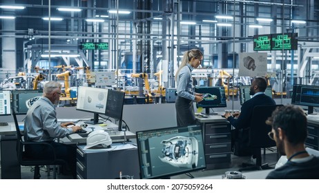 Car Factory: Team Of Automotive Engineers Working, Using Computers To Design Advanced 3D Models For High-Tech Engines. Automated Robot Arm Industrial Assembly Line Manufacturing Electric Vehicles