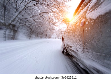 Car and falling snow in winter on forest road with much snow.(Motion blur)