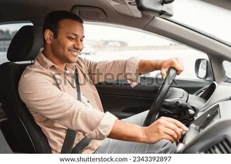 Car Features. Middle Eastern Driver Man Navigating Vehicle And Pushing Buttons On Dashboard Pannel, Driving His New Auto, Turning on Music and Enjoying Road Trip. Side View Shot