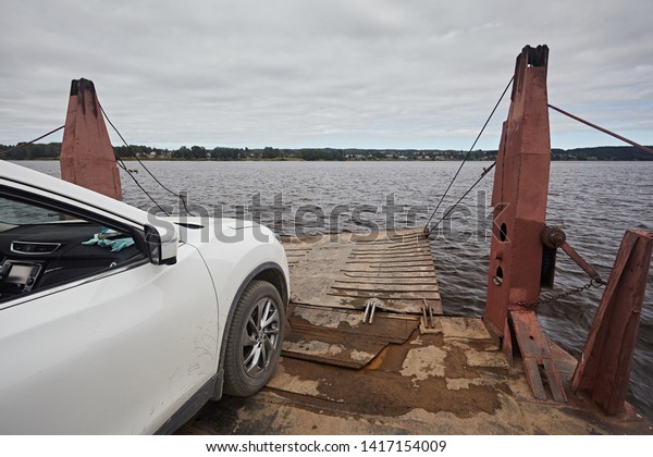 Car ferry - barge for the transport of\
transport on the background of the river in the summer. View of the\
car leaving the loading area with a\
ladder