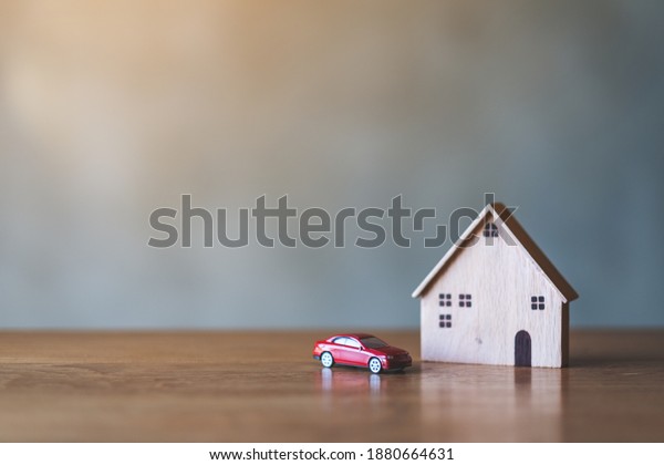 A\
car figure model and wooden house model on the\
table