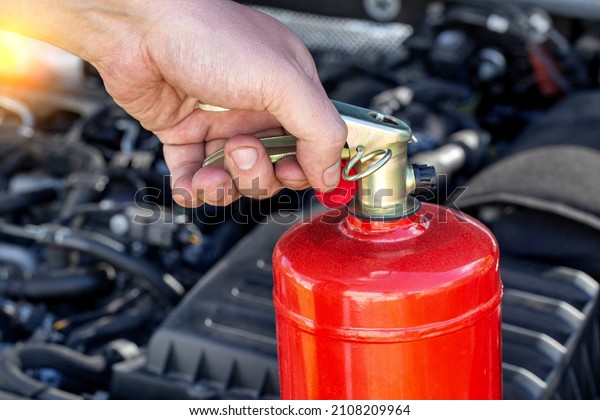 Car fire extinguisher on the background of the car\
engine. Extinguishing class of fire extinguisher, expiration\
date.