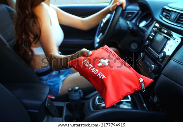 Car First\
Aid Kit in female hands on a steering wheel background. Road\
accident, preparing for a road trip\
concept.