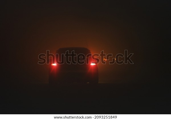 Car in the fog on the winter night road. Low\
visibility concept.