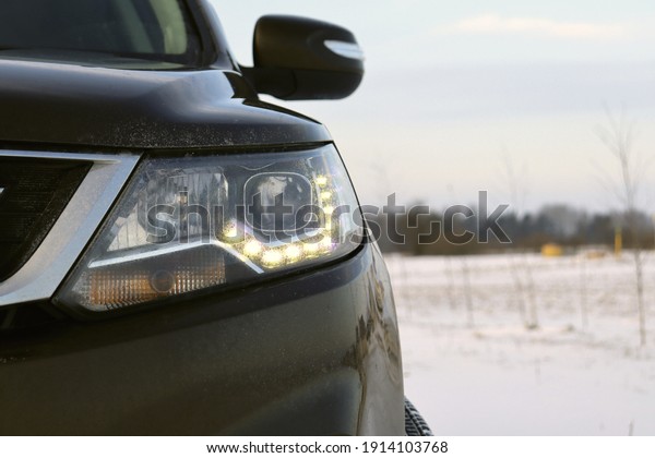 Car front light part of a car in snowy weather\
frozen on a white\
background