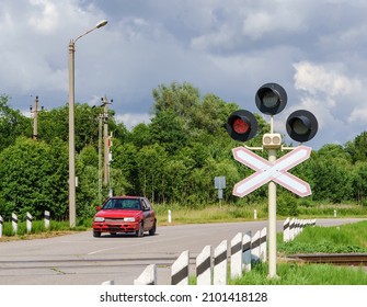 Car in front of a railway crossing. Red traffic light at the railway crossing.
