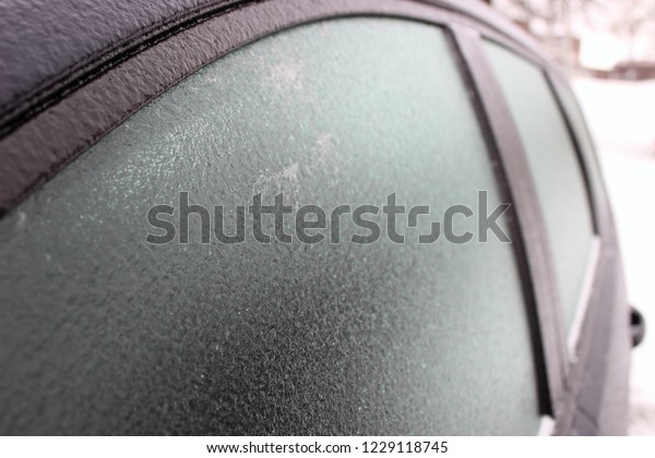 Car with frosted frost-covered window in winter -\
driving safety, heating, preparation for the trip, front-side close\
up view