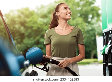 Car Fuel Offer. Smiling Lady Refilling Automobile With Fuel At Modern Petrol Station Standing Near Vehicle Outside, Looking At Gasoline Dispenser Machine. Driver Refueling Her Auto Outdoor