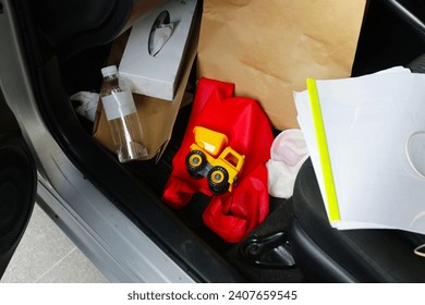 In the car full of belongings, plastic bags, plastic water bottles, document files, paper bags, tissue paper.