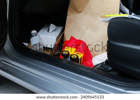 In the car full of belongings, plastic bags, plastic water bottles, document files, paper bags, tissue paper.