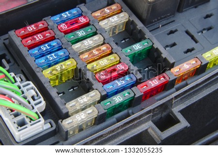 Car fuse box closeup. Multiple rows of different fuses, one connector and part of a relay visible.