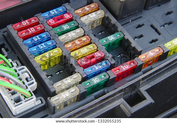 Car fuse box closeup.\
Multiple rows of different fuses, one connector and part of a relay\
visible.