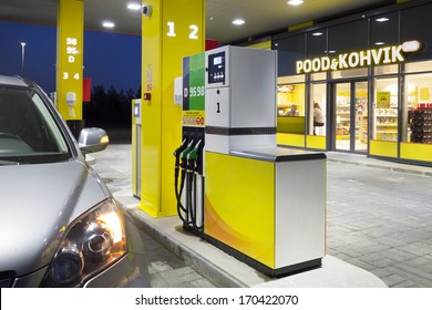 Car In Gas Station. Fuel, Petrol Dispenser, Pump, Handles And Pillars. Fueling. Estonia. Lighted Window Of Convenience Store And Coffe Shop.